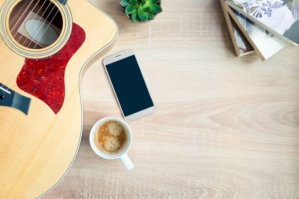 Rahat ev sahnesinin en iyi görünümü. Gitar, kitap, kahve fincanı, telefon ve ahşap arka plan üzerinde lezzetli bitkiler. Kopya alanı, mock-up.