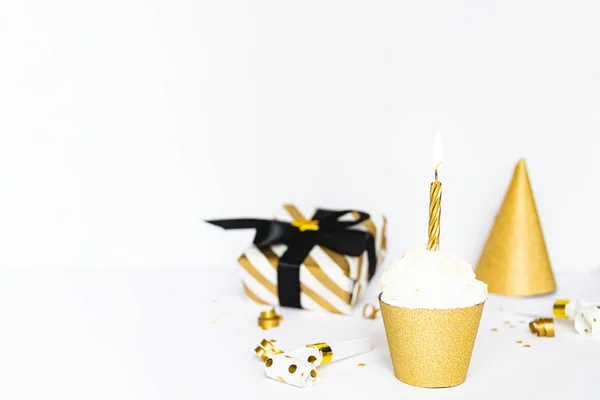 Altın renkte ışıklı mum ve parti aksesuarları ile Cupcake.