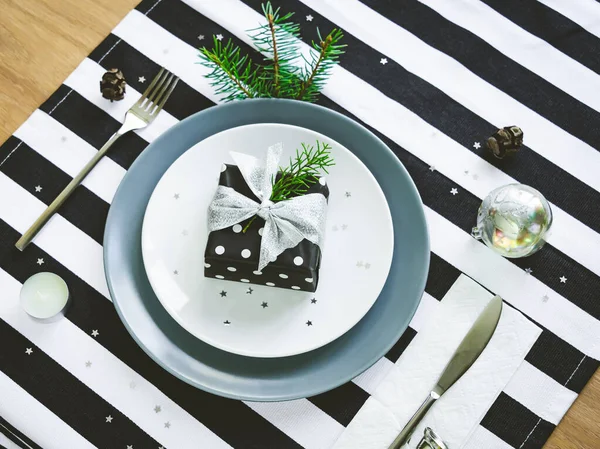 Draufsicht auf die weihnachtliche Tischdekoration. eine Geschenkschachtel im Teller. — Stockfoto