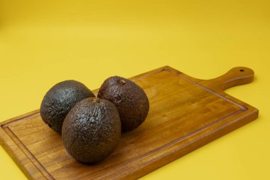 Avokadoların tamamını, sarı bir arka plana karşı ahşap bir tahtaya yerleştirin.