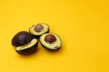Sarı arka plana yerleştirilmiş dilimlenmiş Avokadoların yakın plan görüntüsü