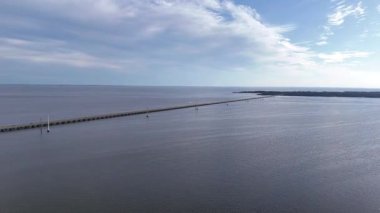 Kill Devil Hills ve Point Harbor arasında sakin bir denizi geçerek uzak ufka doğru düz bir Wright Memorial köprüsünün havadan görüntüsü. Güneş suda parlıyor, huzur verici bir sahne yaratıyor..