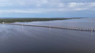 Kill Devil Hills ve Point Harbor arasında sakin bir denizi geçerek uzak ufka doğru düz bir Wright Memorial köprüsünün havadan görüntüsü. Güneş suda parlıyor, huzur verici bir sahne yaratıyor..