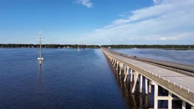 Kill Devil Hills ve Point Harbor arasında sakin bir denizi geçerek uzak ufka doğru düz bir Wright Memorial köprüsünün havadan görüntüsü. Güneş suda parlıyor, huzur verici bir sahne yaratıyor..