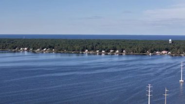 Kill Devil Hills ve Point Harbor arasında sakin bir denizi geçerek uzak ufka doğru düz bir Wright Memorial köprüsünün havadan görüntüsü. Güneş suda parlıyor, huzur verici bir sahne yaratıyor..