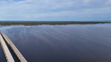 Kill Devil Hills ve Point Harbor arasında sakin bir denizi geçerek uzak ufka doğru düz bir Wright Memorial köprüsünün havadan görüntüsü. Güneş suda parlıyor, huzur verici bir sahne yaratıyor..