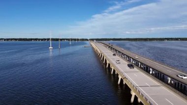 Kill Devil Hills ve Point Harbor arasında sakin bir denizi geçerek uzak ufka doğru düz bir Wright Memorial köprüsünün havadan görüntüsü. Güneş suda parlıyor, huzur verici bir sahne yaratıyor..