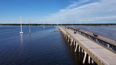 Kill Devil Hills ve Point Harbor arasında sakin bir denizi geçerek uzak ufka doğru düz bir Wright Memorial köprüsünün havadan görüntüsü. Güneş suda parlıyor, huzur verici bir sahne yaratıyor..