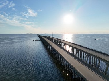 Kill Devil Hills ve Point Harbor arasında sakin bir denizi geçerek uzak ufka doğru düz bir Wright Memorial köprüsünün havadan görüntüsü. Güneş suda parlıyor, huzur verici bir sahne yaratıyor..