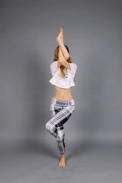 스포티 한 아름 다운 젊은 여자 요가 연습, 회색 및 흰색 운동복, 스튜디오, 전체 길이 입고 운동 — 스톡 사진