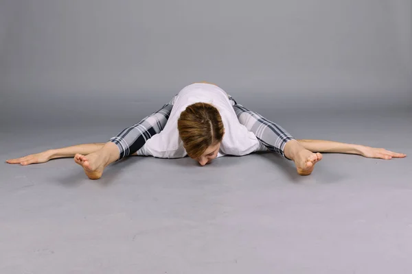 Deportiva hermosa joven practicando yoga, ejercitándose vistiendo ropa deportiva gris y blanca, estudio, larga duración — Foto de Stock