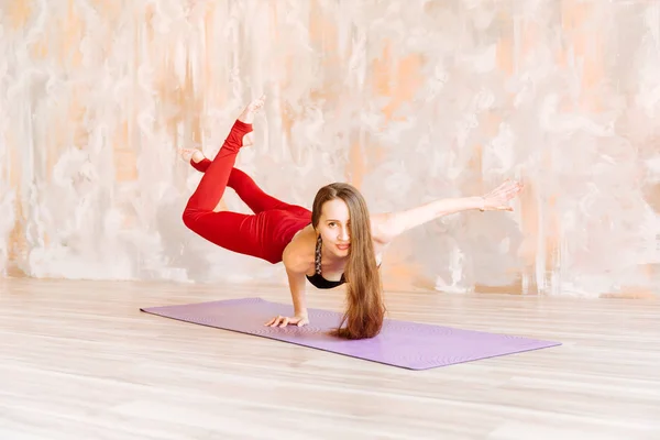 Yoga flicka i svart topp och röda leggings står på ena handen på mattan — Stockfoto