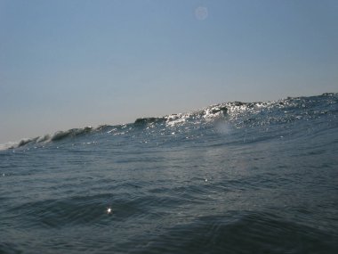 Sahilde kırılan dalgalar, sprey, beyaz su ve ışık suyun yüzeyine yansıyor..