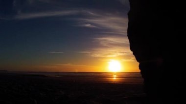 Hızlandırılmış bir taş, kum, plaj dalgalar ve bulutlar günbatımı sırasında hareket hızlı