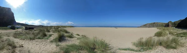 在夏季阳光明媚的日子里 大西洋上的海滩或海湾的全景图片上有沙子 高高的岩石和蓝天和云彩 — 图库照片