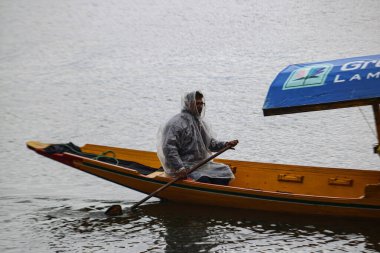 2 Mart 2024, Srinagar, Hindistan: Bir adam Srinagar 'da yağmur yağarken dal gölünde kürek çekiyor. Bitmek bilmeyen yağmur büyüsü sırılsıklam olmuş düzlüklerde