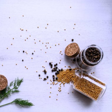 Yellow mustard seeds and black pepper isolated on a white background.