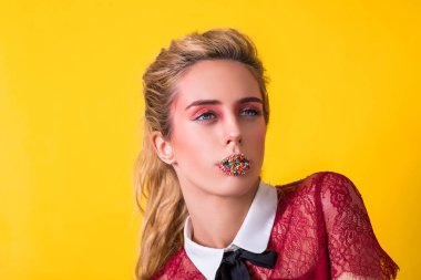 Dudaklar serpin şekerle kaplı. Yaratıcı makyaj. Şehvetli dudakları. Moda makyaj, saç modeli. Seksi ağız. Güzel kadın kız moda. Güzel yüzü mavi gözlü seksi ağız. Sarı izole.