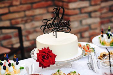 Doğum günü pastası ile kırmızı gül. Muhteşem 30. Özel bir pasta 30 yaşında. Birhday parti açık tatlı masaya. Beyaz yuvarlak pasta çiçek.