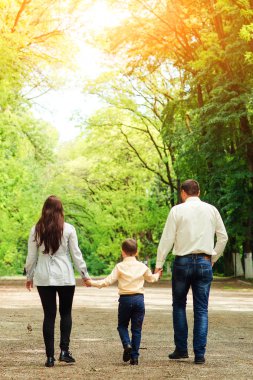 Mutlu bir aile açık havada eğleniyor. Genç Anne, baba ve oğullarının Park'ta yürüyordunuz. Mutlu bir aile birlikte güneşli bir günde dinleniyor. Aile hafta sonu.