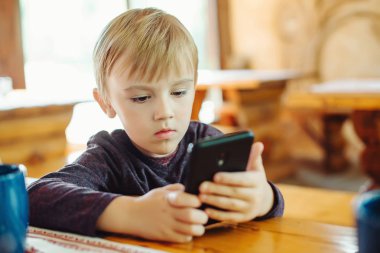 Smartphone oyun oynayan çocuk. Küçük çocuk ile internet kullanımı smartphone. Teknoloji kavramı. Okul öncesi çocuk oyunları oynamak ve karikatürler cep telefonu izlemek