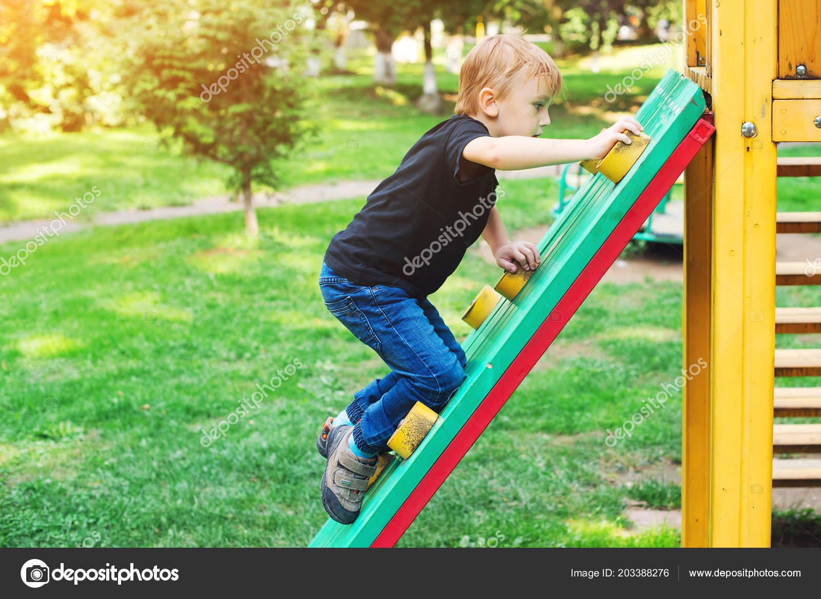 Young child blond boy climbing rope net in playground summer Stock