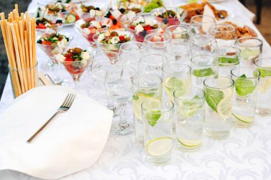 Açık havada parti için yemek servisi. Açık büfe yemek bazı Festival olay, parti veya düğün yemek servisi. Limon ve nane ile su. Tablo, Ziyafet gıda bardaklarda Yunan salatası. Ikram Servisi