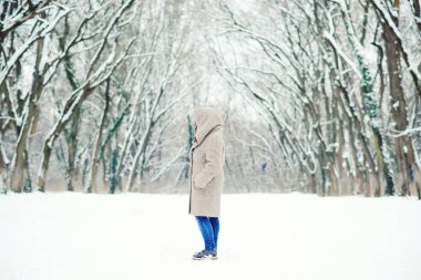 Woman in the snowy winter forest. Winter girl walking in winter park outdoor. Winter fashion concept. Winter holidays. Beautiful winter landscape. Snowy winter morning clipart