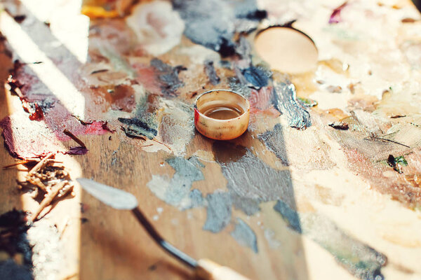 Workplace painter palette with colors and brushes. Palette of colors, creative disorder, art. Artist's palette, close-up. Background image of bright oil-paint palette closeup