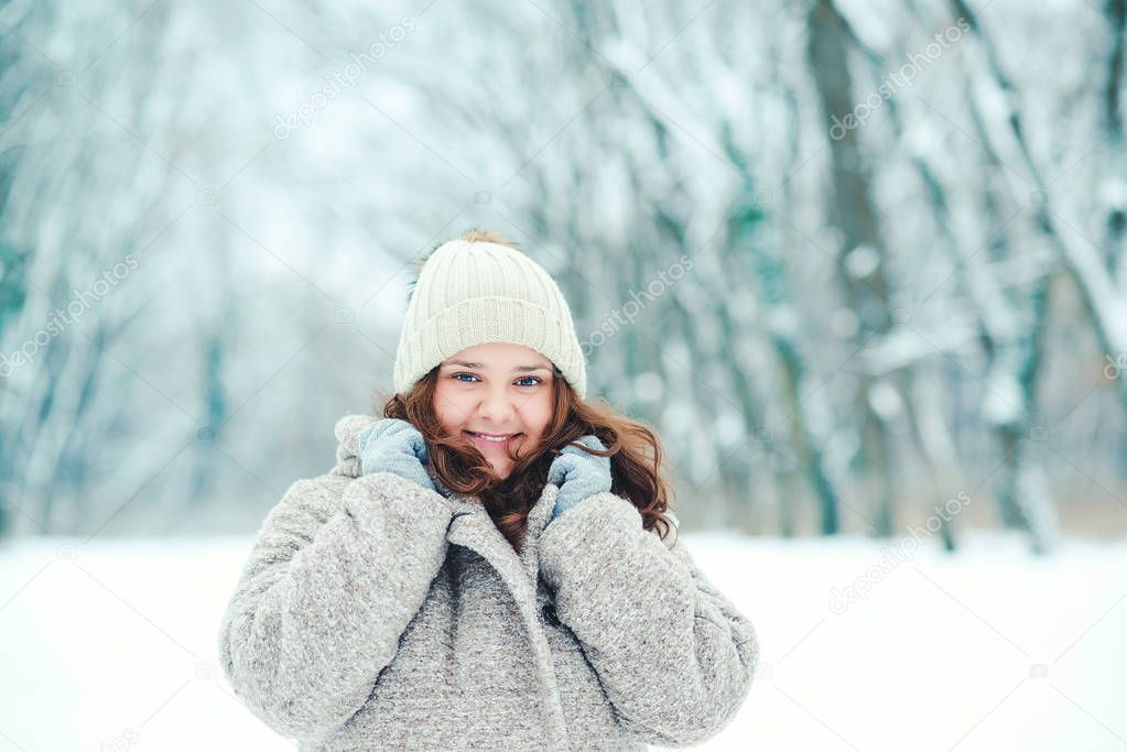 Teenage girl posing in snowy forest. Winter holidays concept. Girl outdoors in cold day. Winter fashion, sales and lifestyle concept. Winter woman portrait. Warm woman outfit. Winter mood