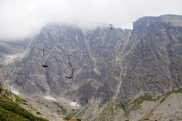 Cabin lift to the mountain. Mountain landscape in High Tatry. Chairlift at the ski resort in a cloud. Ski lift, cable car cabin in mountain background