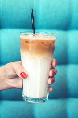 Buzlu latte kahve. Buzlu cam tutan el kadın kahve mavi arka plan üzerinde