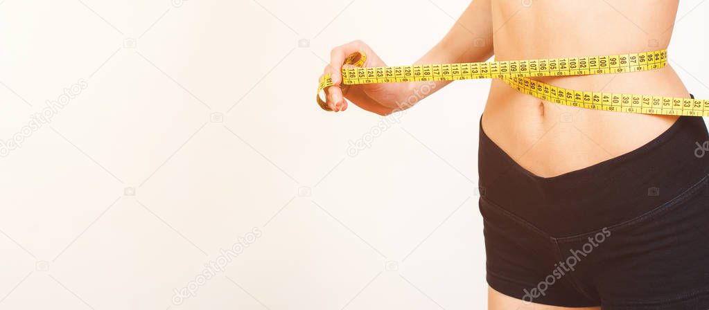 Woman measuring her waist. Perfect Slim Body. Diet. Slim body, isolated on white, copy space. Fit fitness girl measuring her waistline with measure tape. Fintess, diet and healthy lifestyle concept