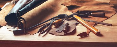 Shoemaker'ın çalışma masası. Araçlar ve deri ayakkabı tamircisine işyerinde. Ahşap arka plan üzerinde deri el sanatları araçlar kümesi. Ahşap masa üstünde Ayakkabı maker alet