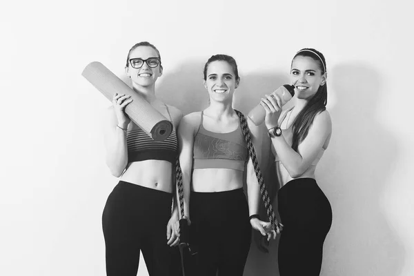 一群年轻的运动女孩在健身房 女孩在健身锻炼后休息 健康饮食和生活方式的概念 穿着瑜伽垫的运动妇女站在白色的墙上 女孩在运动服 — 图库照片