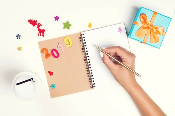 2019 Goals plans dreams. Make to do list for new year. Christmas concept. Writing in notebook. Woman hand holding pen on notebook. New year winter holiday Christmas.