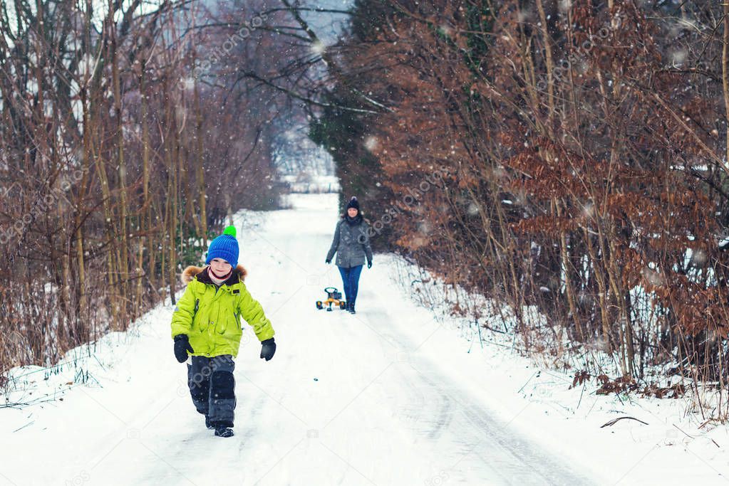 Happy family walking in winter forest. Winter weather. Happy mother and her son enjoying snowy winter day. Christmas vacation. Winter holidays.