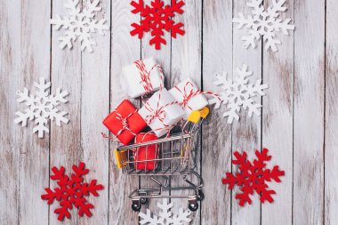 Noel alışveriş arka plan. Noel satış. Oyuncak süpermarket arabası hediye dolu. Kış alışveriş arka plan. Hediyeler ile renkli kar taneleri. Yeni yıl alışveriş kavramı. Yılbaşı sepeti