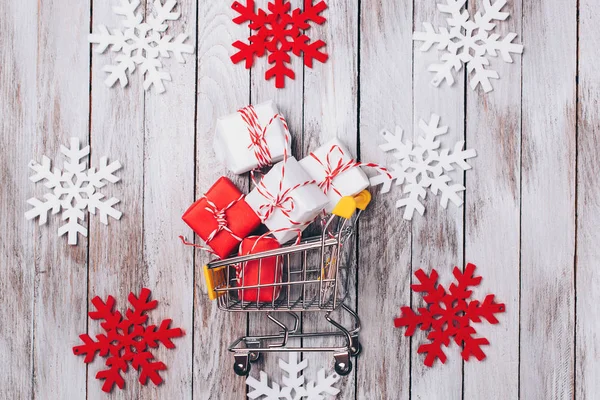 Christmas shopping background. Christmas sales. Toy supermarket trolley full of gifts. Winter shopping background. Colored snowflakes with gifts. New Year shopping concept. Shopping christmas cart