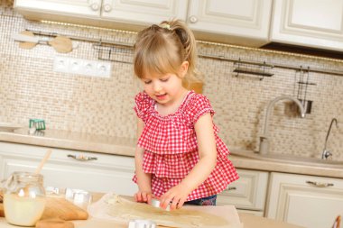 Mutlu çocuk kız mutfak yemek pişiriyor. Çocuk kızı çerezleri pişiren. Mutlu çocukluk. Bir mutfak üzerinde küçük yardımcısı. Güzel aile. Sevimli küçük kız evde. Noel ya da Paskalya Tatilleri