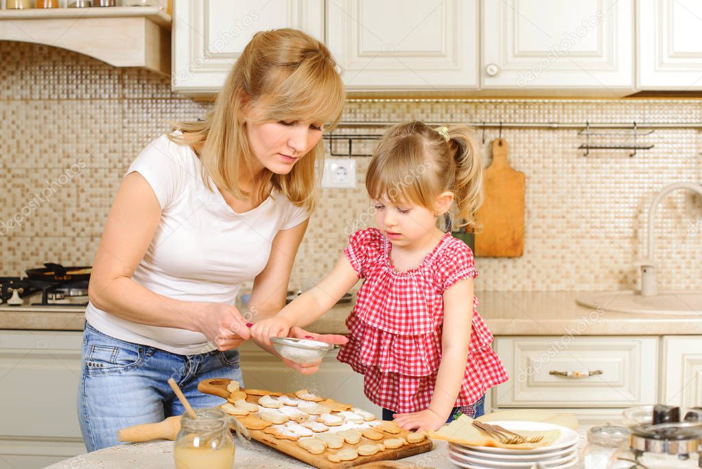 Mother and daughter are cooking cookies. Mom and child having fun in the kitchen. Homemade food and little helper. Holidays cookies. Happy family. Baking in kitchen. Christmas or Easter holidays