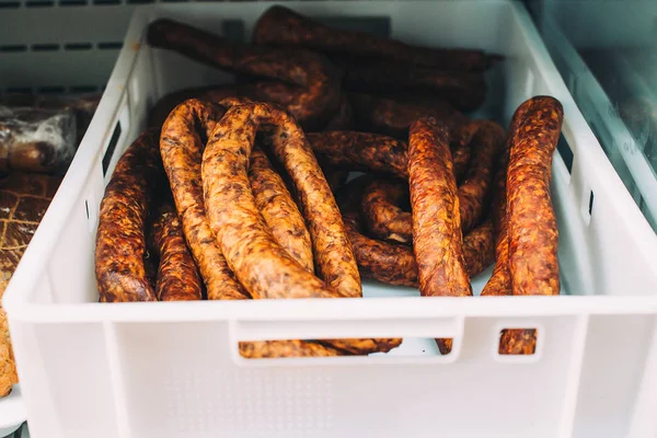 Homemade sausages on a farmers market. Traditional street food. Tasty delicious smoked dried sausages at plastic box.