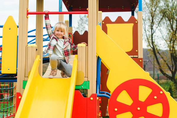 Cute little girl on a slide, outdoors. Adorable funny girl at modern colorful playground
