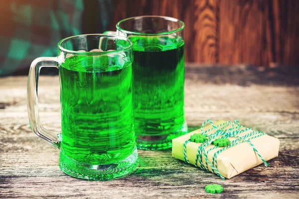 Histórico do Dia de São Patrício. Duas canecas de cerveja verde, lanche e caixa de presente para celebração . — Fotografia de Stock