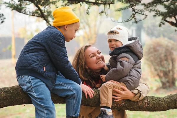 Mãe feliz e crianças no passeio no parque. Família feliz jogando ao ar livre em tempo frio . — Fotografia de Stock