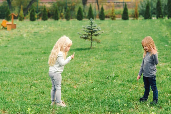 Två söta små systrar ha kul i trädgården. Happy Kids leker utomhus. Natur och fritid kul för familjen. — Stockfoto