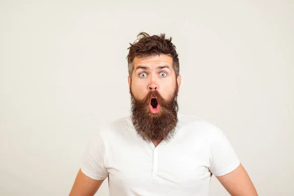 Un hombre barbudo impactado mira fijamente a la cámara. barbudo hipster chico ampliamente abierto boca y ojos . — Foto de Stock