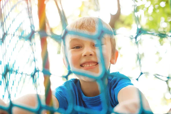 Little boy playing at rope adventure park. Summer holidays concept. Cute child having fun in net tunnel. — Stock Photo, Image