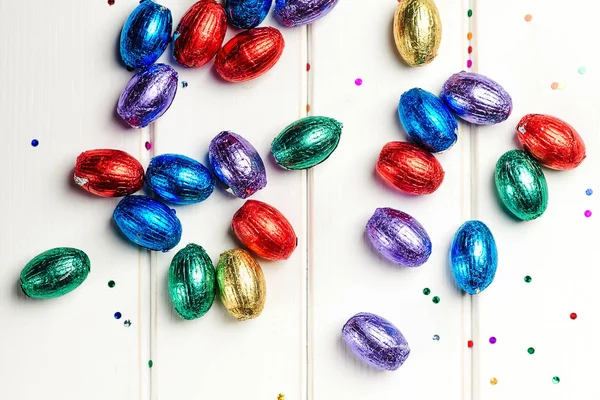 Oeufs en chocolat de Pâques en feuille colorée sur fond blanc. Fond de Pâques, plat. Les ventes de Pâques. Joyeuses fêtes de Pâques . — Photo