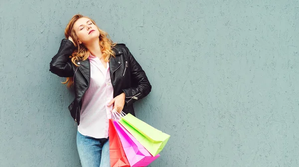 Κομψό κορίτσι που απολαμβάνει μετά από υπέροχα ψώνια. Η πωλήτρια που κρατάει σακούλες για ψώνια. Κορίτσι που ποζάρει στον γκρίζο τοίχο, αντιγράφει χώρο. Καταναλωτισμός, ψώνια, πωλήσεις και lifestyle. — Φωτογραφία Αρχείου
